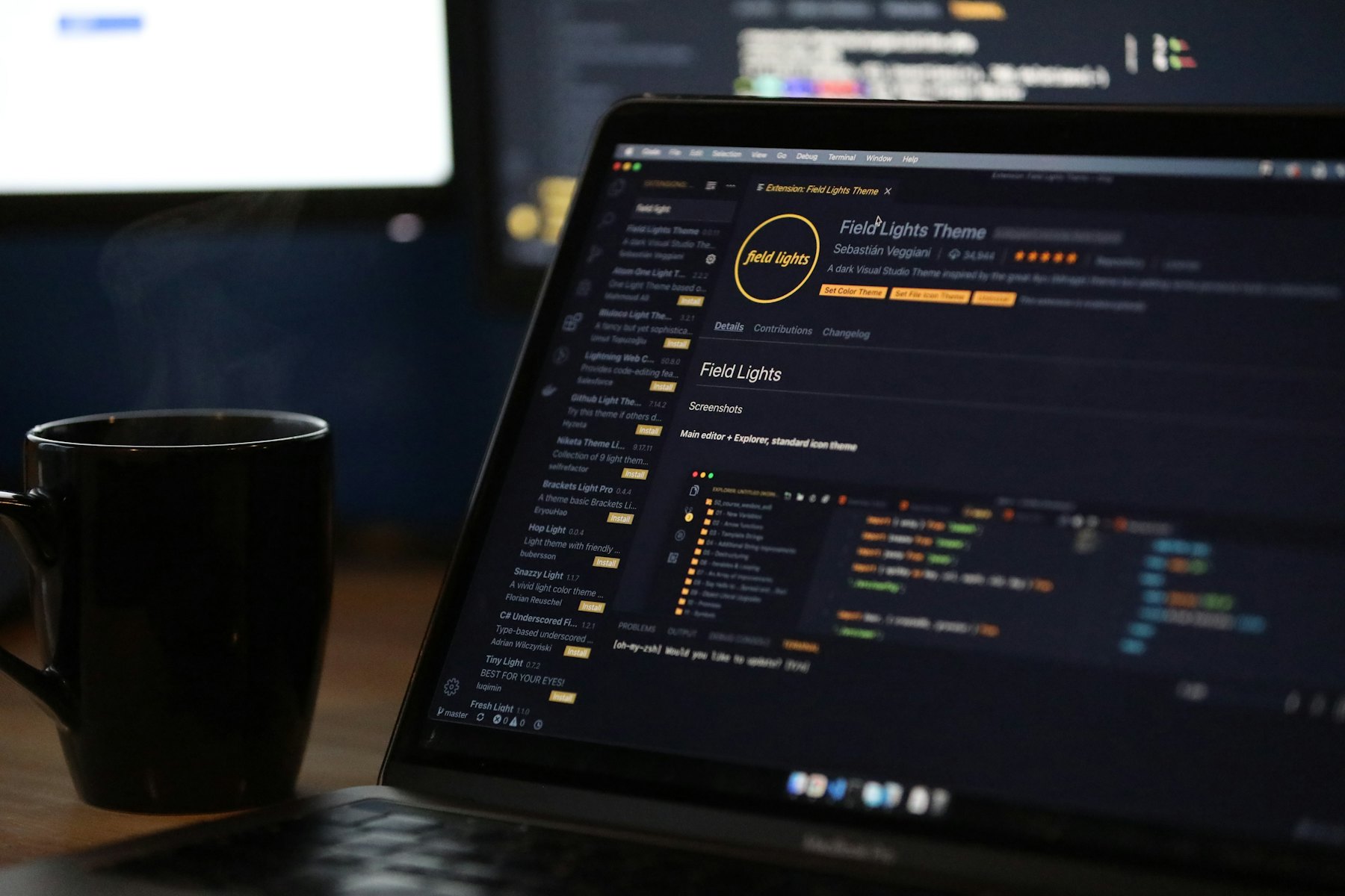 暗い机の上、CMSの管理画面を開いたノートパソコンとコーヒーカップ